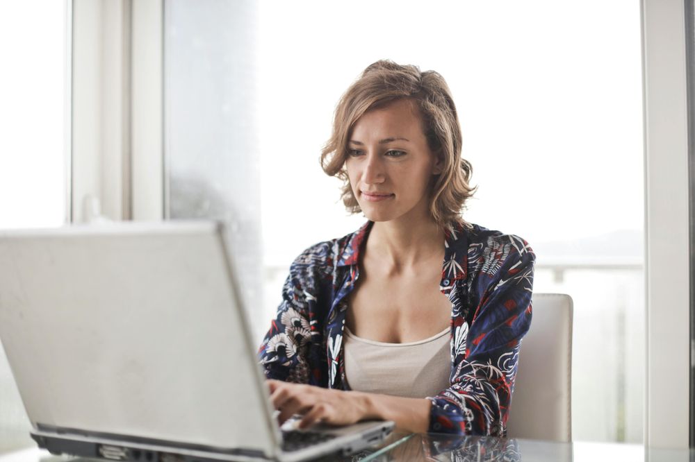 Eine Frau sitzt an einem Tisch und arbeitet am Laptop