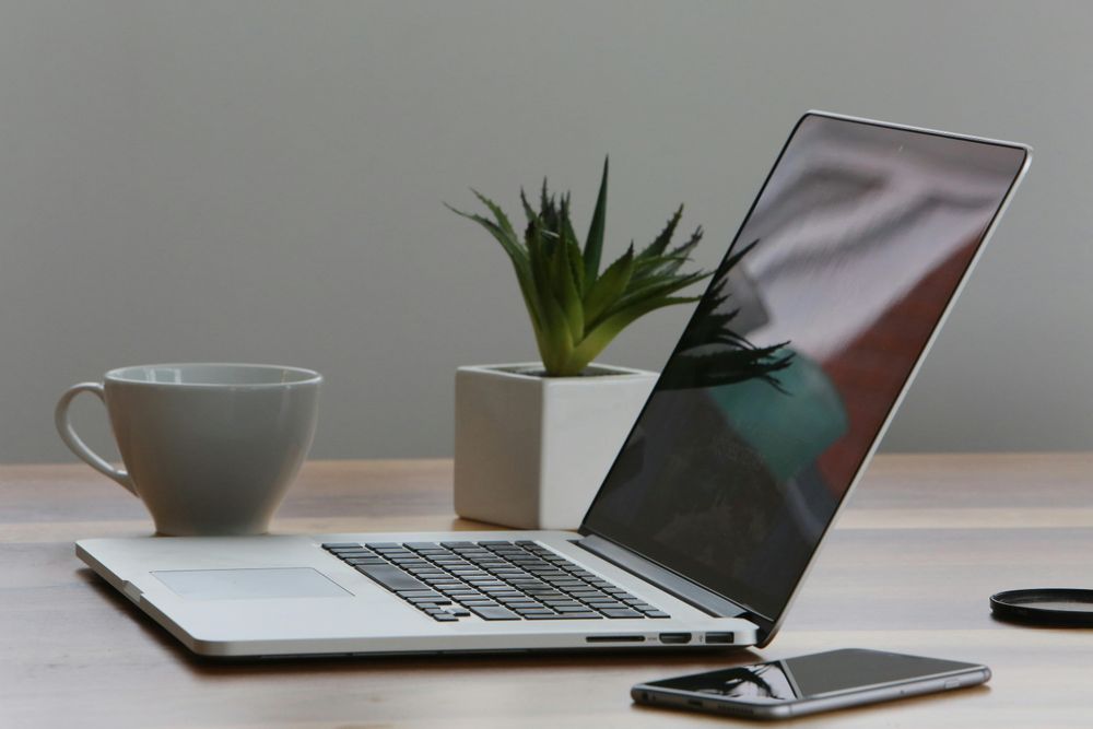 Ein Laptop, Handy und eine Tasse auf einem Tisch
