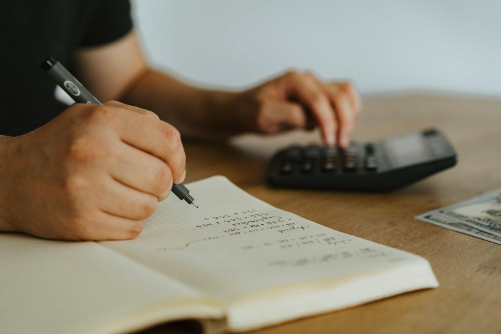 Ein Mann sitzt am Schreibtisch und rechnet etwas mit dem Taschenrechner