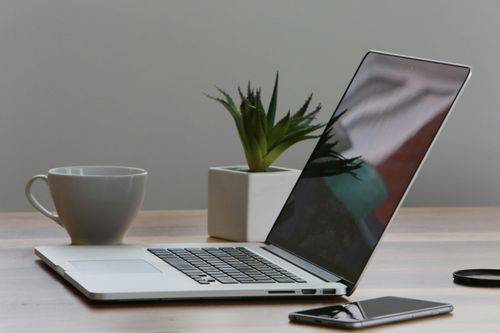 Ein Laptop, Handy und eine Tasse auf einem Tisch