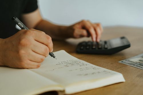 Ein Mann sitzt am Schreibtisch und rechnet etwas mit dem Taschenrechner