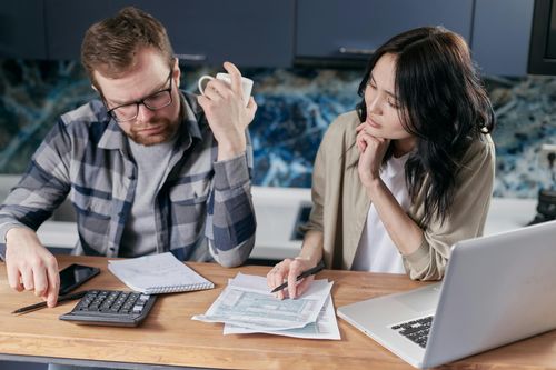 Eine Frau und ein Mann sitzen am Schreibtisch und analysieren Unterlagen