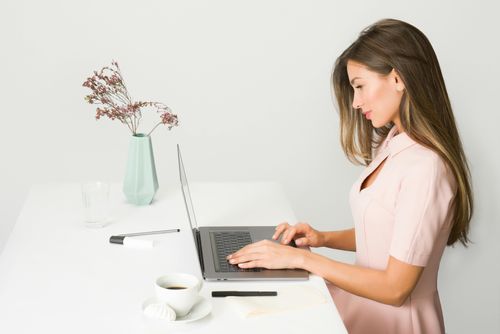 Eine Frau sitzt an einem Schreibtisch und arbeitet an einem Laptop.